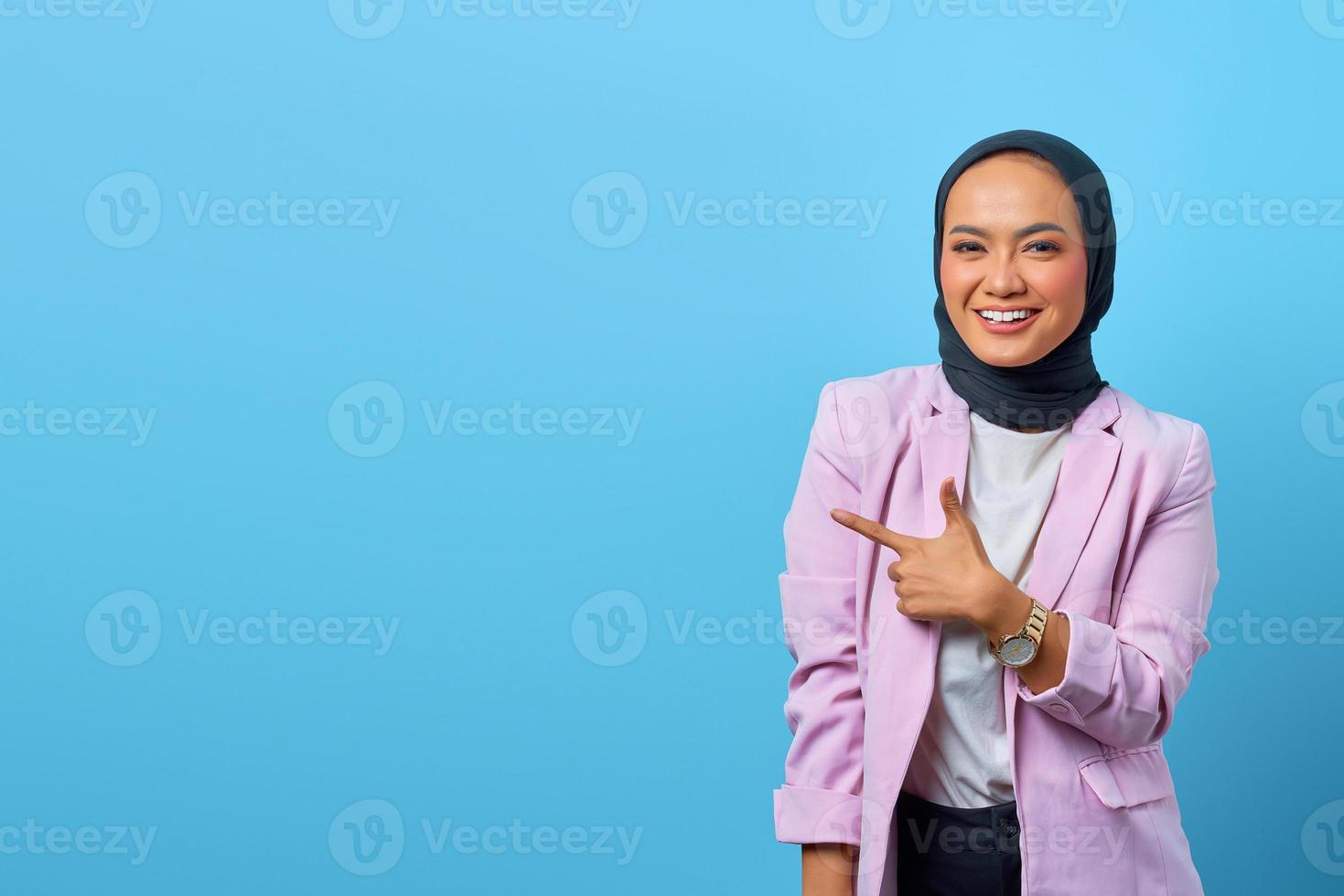 Cheerful Asian woman pointing fingers to empty space photo