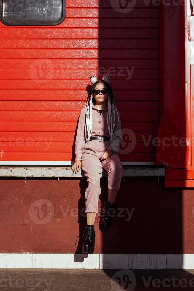 Beautiful cool girl over urban wall. Sunny day. Girl in sunglasses photo