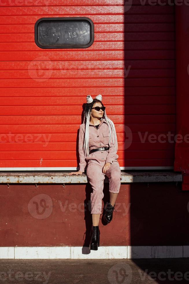 Beautiful cool girl over urban wall. Sunny day. Girl in sunglasses photo