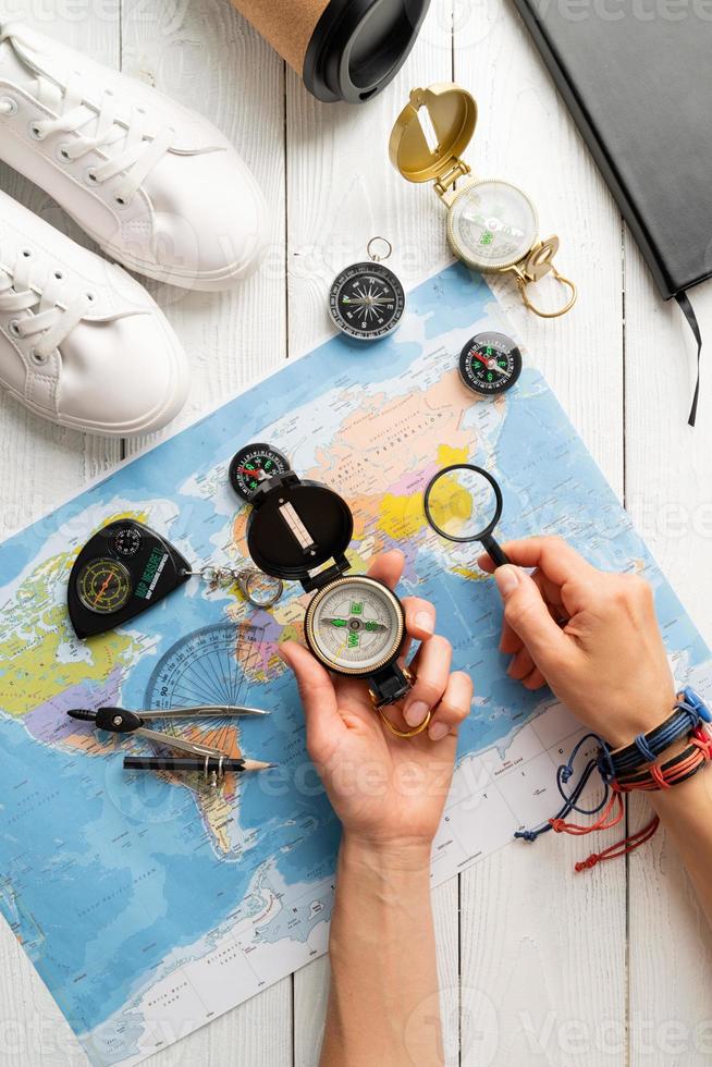 Top view woman planning a trip, holding compass and magnifying glass photo