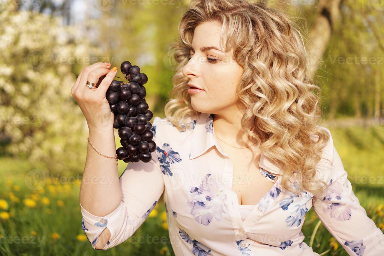 Mujer con uva en un picnic en el jardín de verano foto