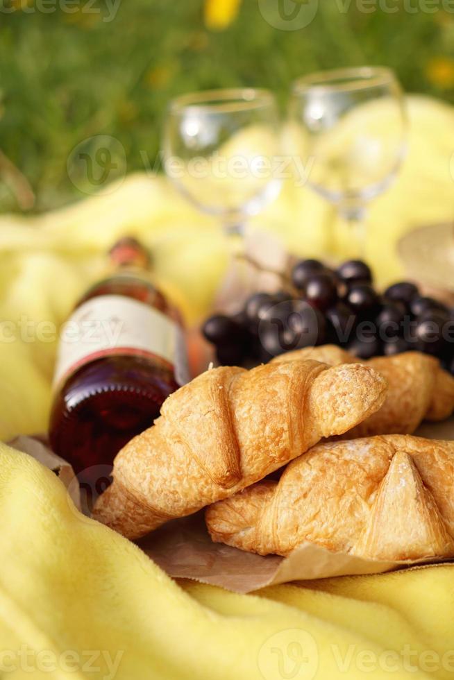 picnic en la hierba con croissant, vino rosado, sombrero de paja, uva foto