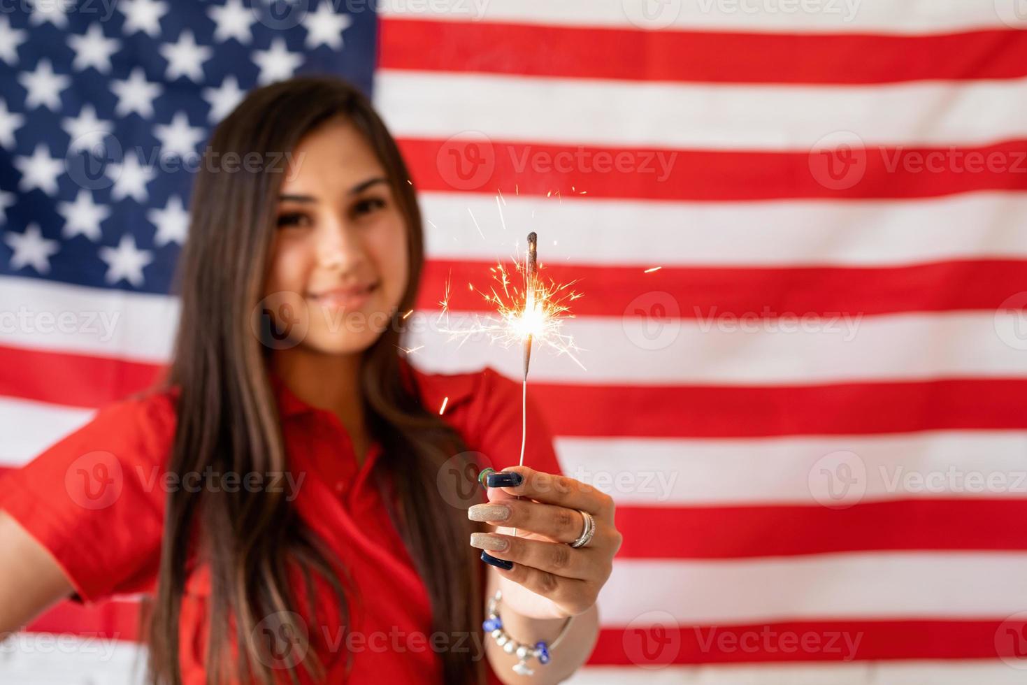 Bella mujer sosteniendo una bengala en el fondo de la bandera de Estados Unidos foto