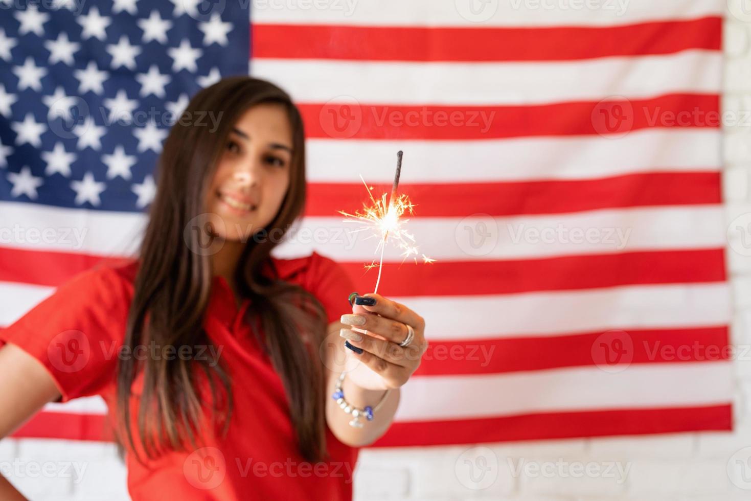 Bella mujer sosteniendo una bengala en el fondo de la bandera de Estados Unidos foto