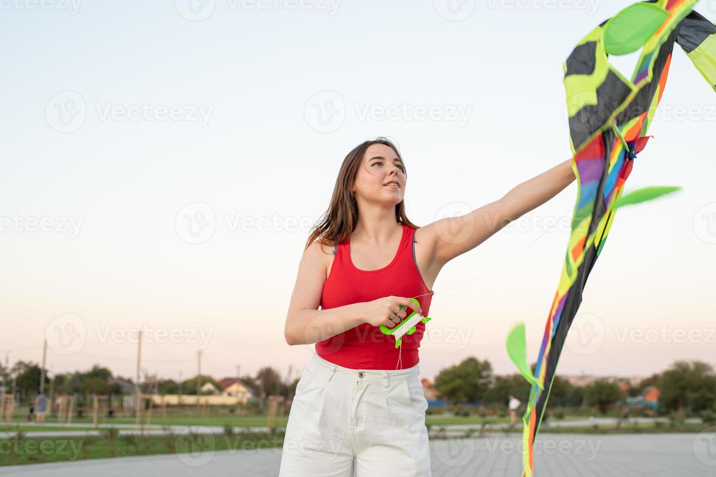 Mujer joven volando una cometa en un parque público al atardecer foto