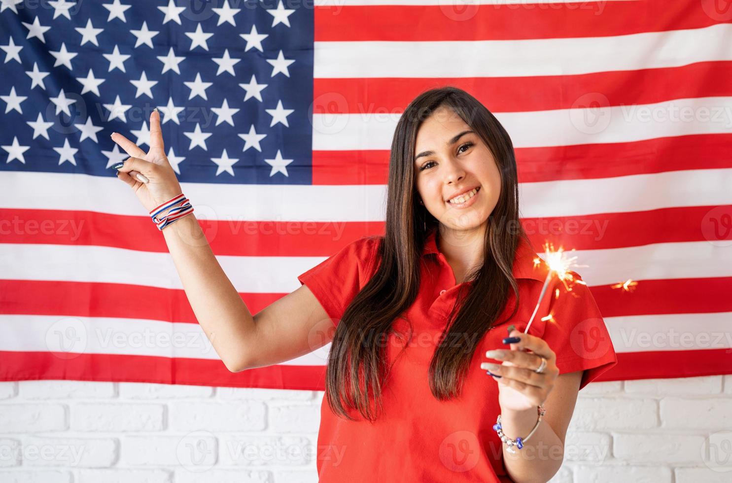 Beautiful woman holding a sparkler on US flag background photo