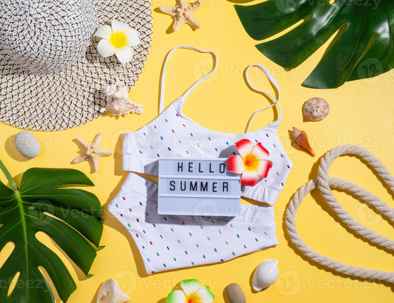 Words Hello Summer on the lightbox with swimming suit, tropical leave photo