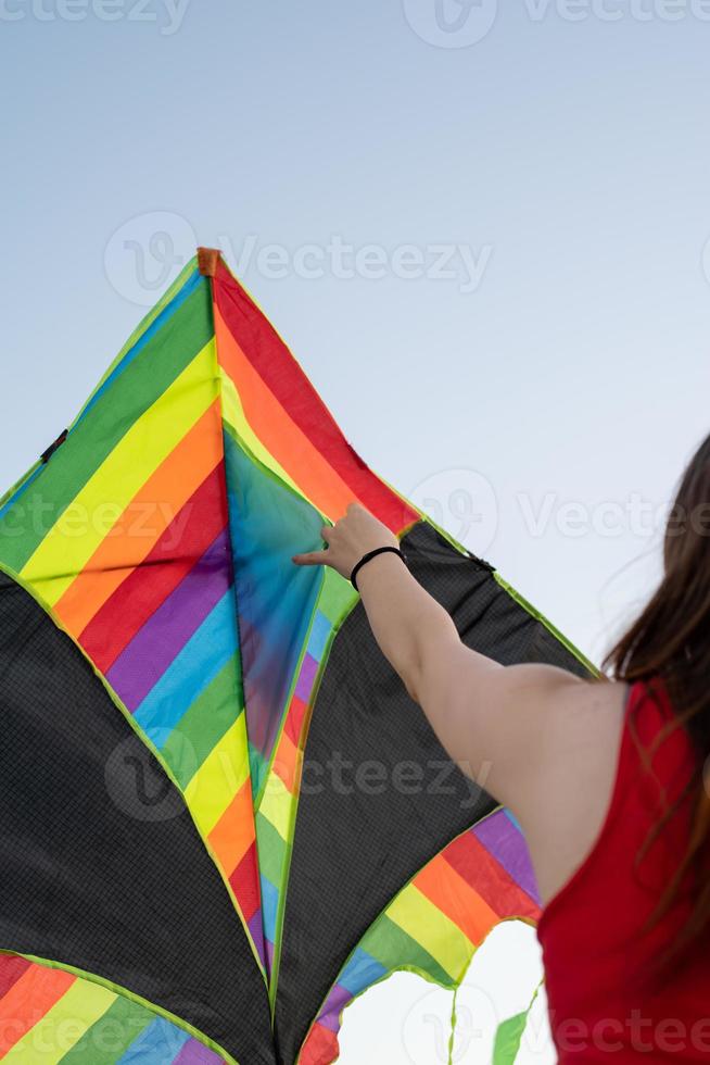 Mujer joven volando una cometa en un parque público al atardecer foto