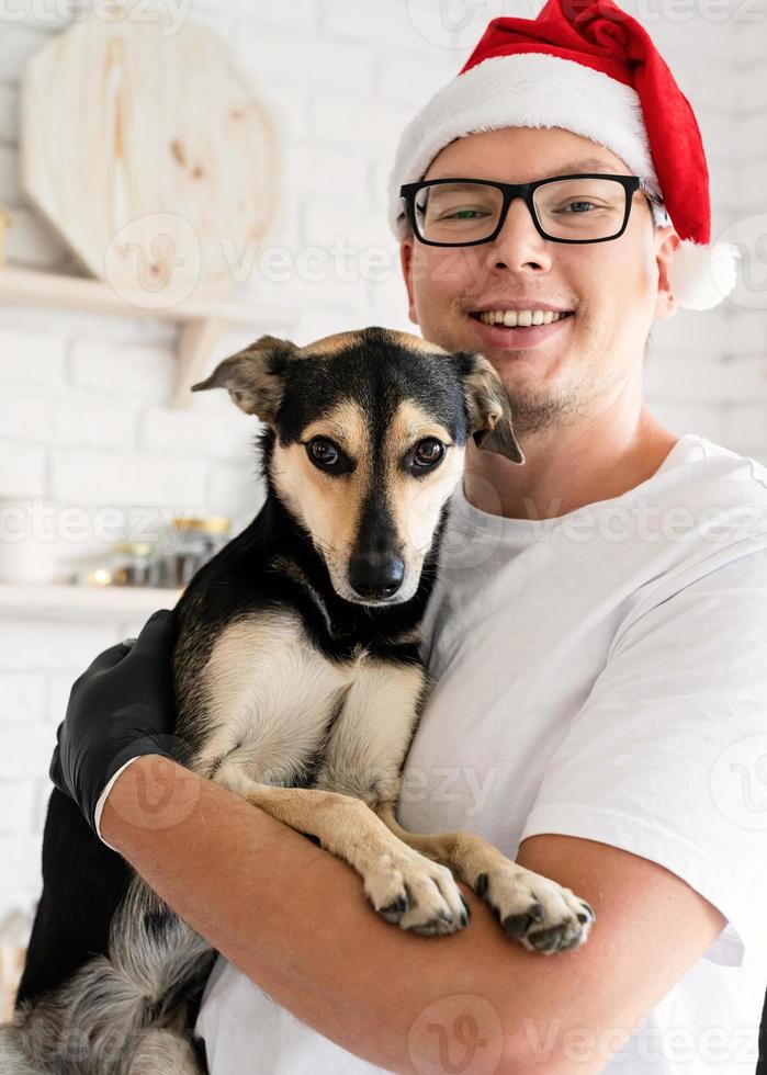 Handsome hipster with his dog cooking christmas cake in a kitchen. photo