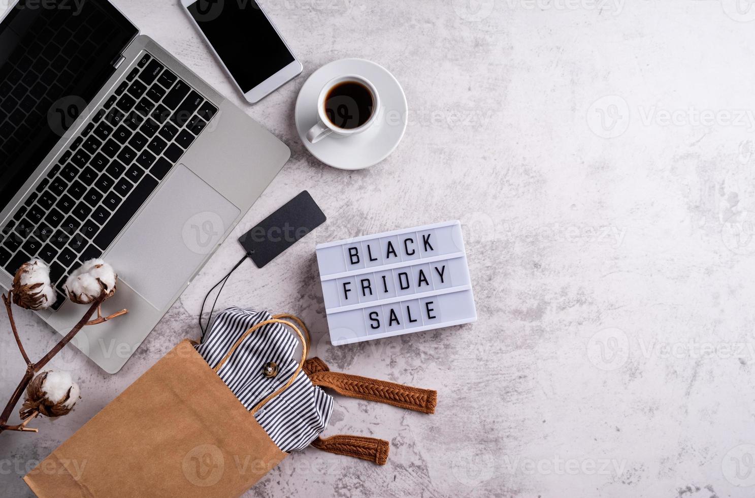 Palabras de venta de viernes negro en caja de luz con taza de café, computadora portátil foto