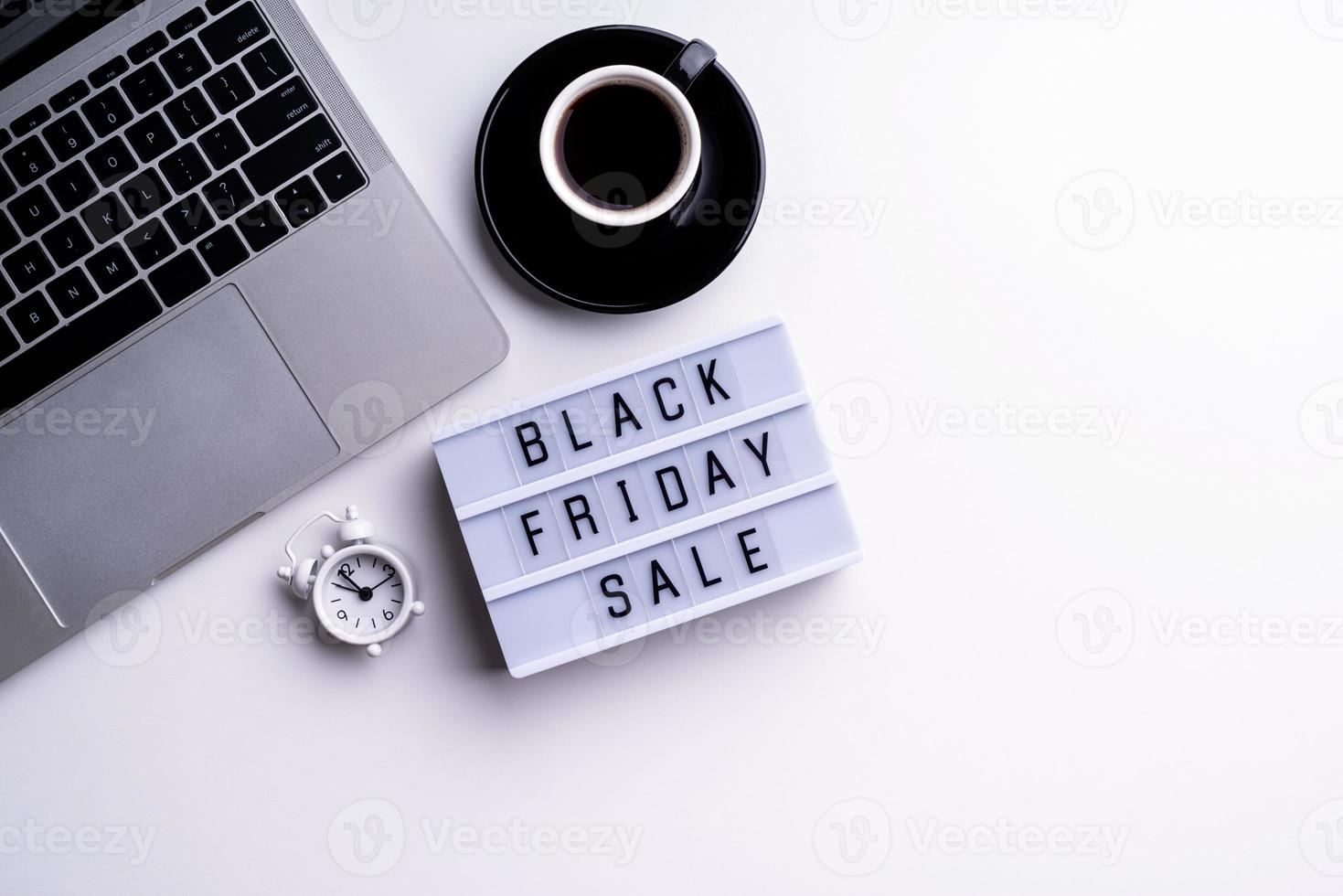 Black Friday Sale words on lightbox with cup of coffee, laptop photo