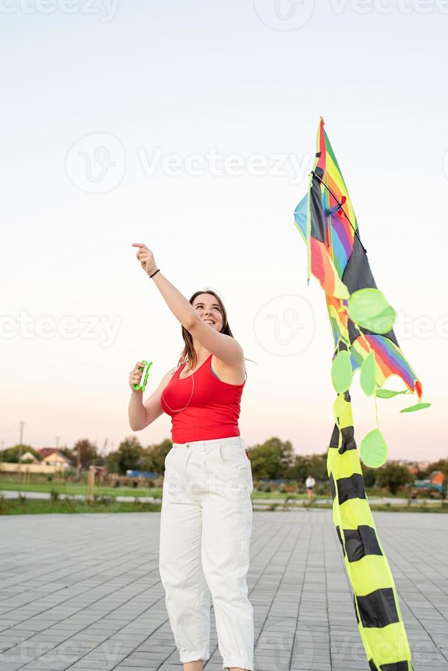 Young woman flying a kite in a public park at sunset photo