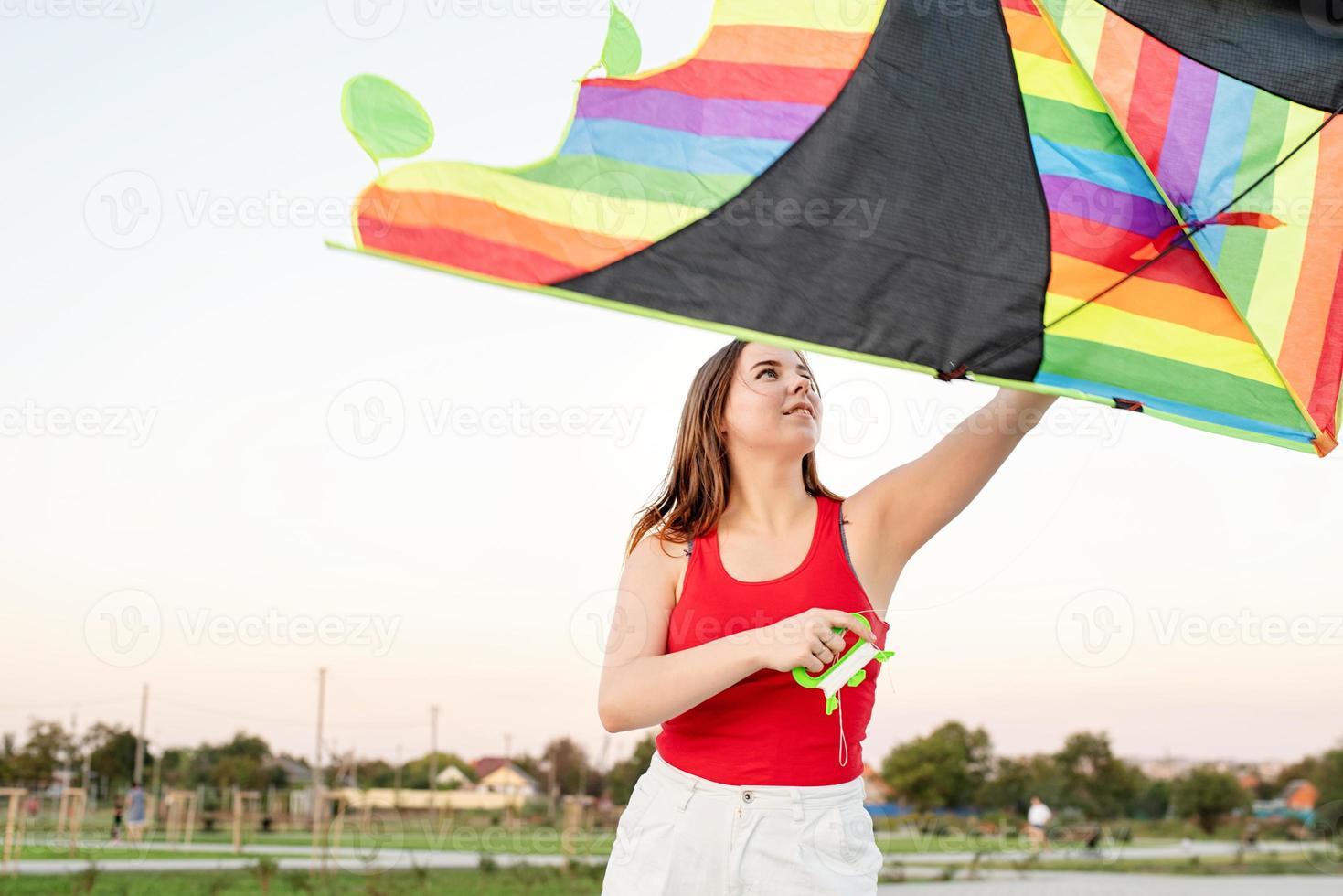 Young woman flying a kite in a public park at sunset photo