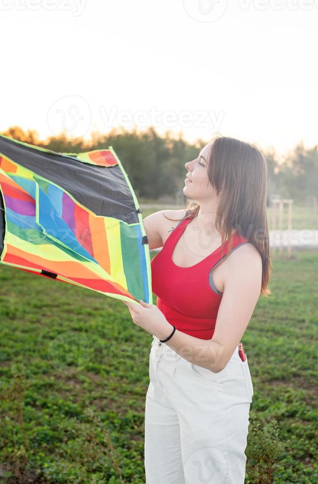 Mujer joven volando una cometa en un parque público al atardecer foto