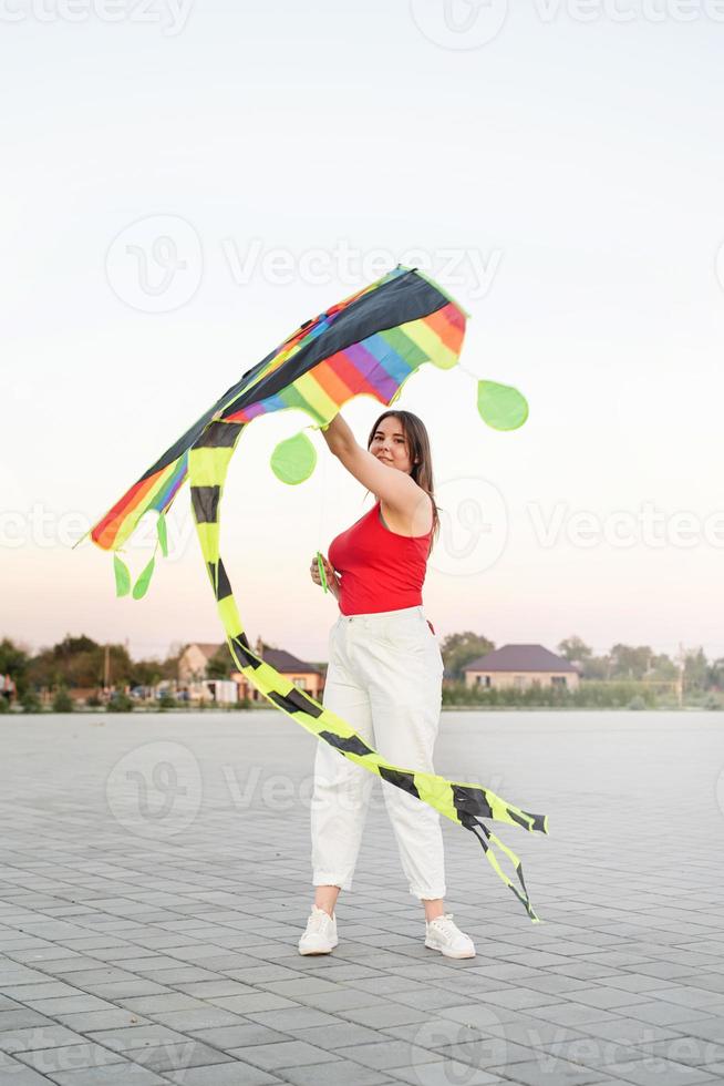 Mujer joven volando una cometa en un parque público al atardecer foto