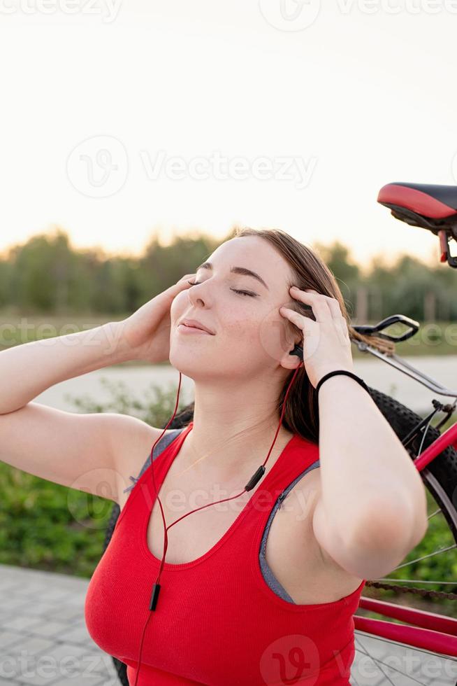 Teenage girl sitting next to her bike listening to the music photo