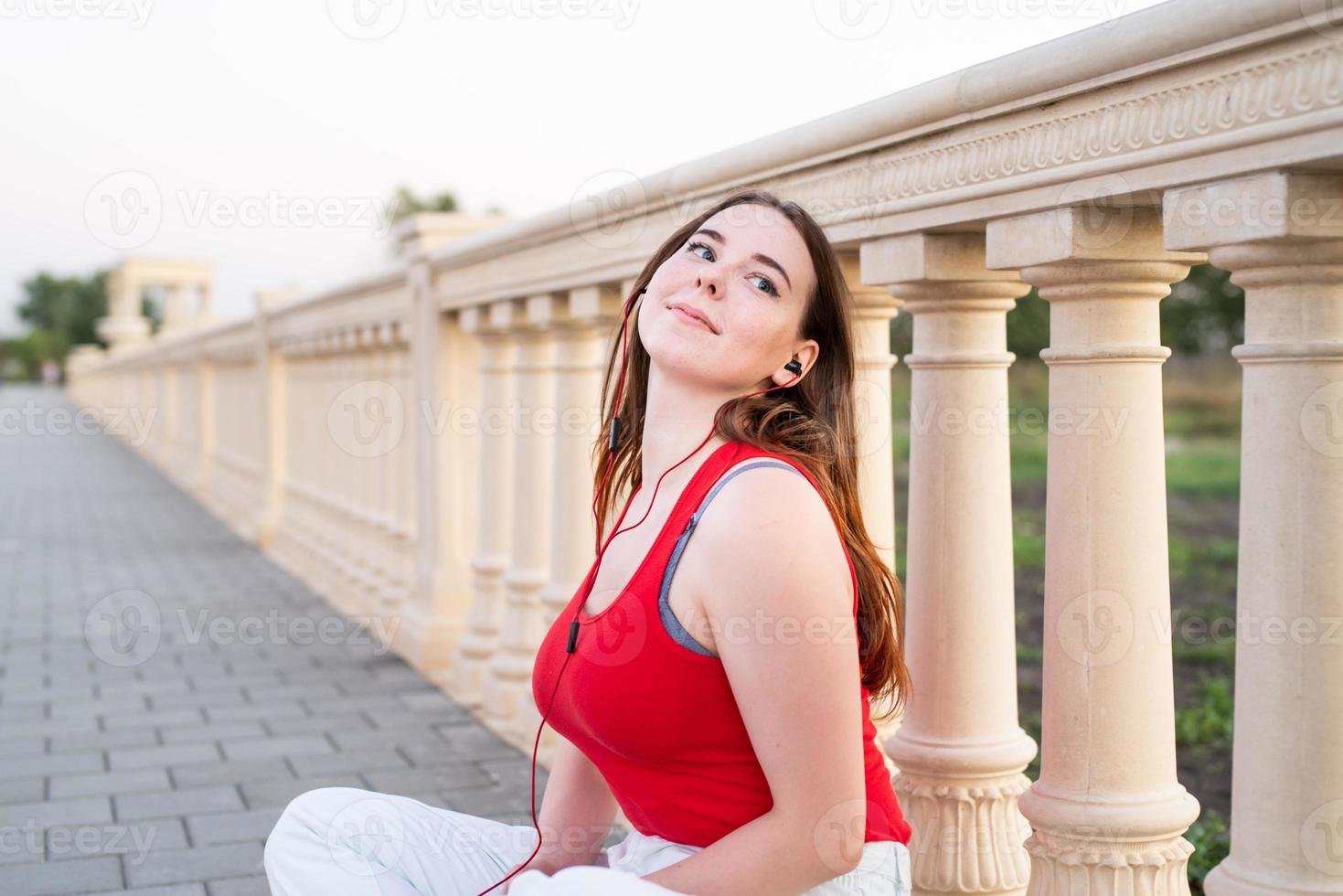 Adolescente sentada junto a la columna escuchando música. foto