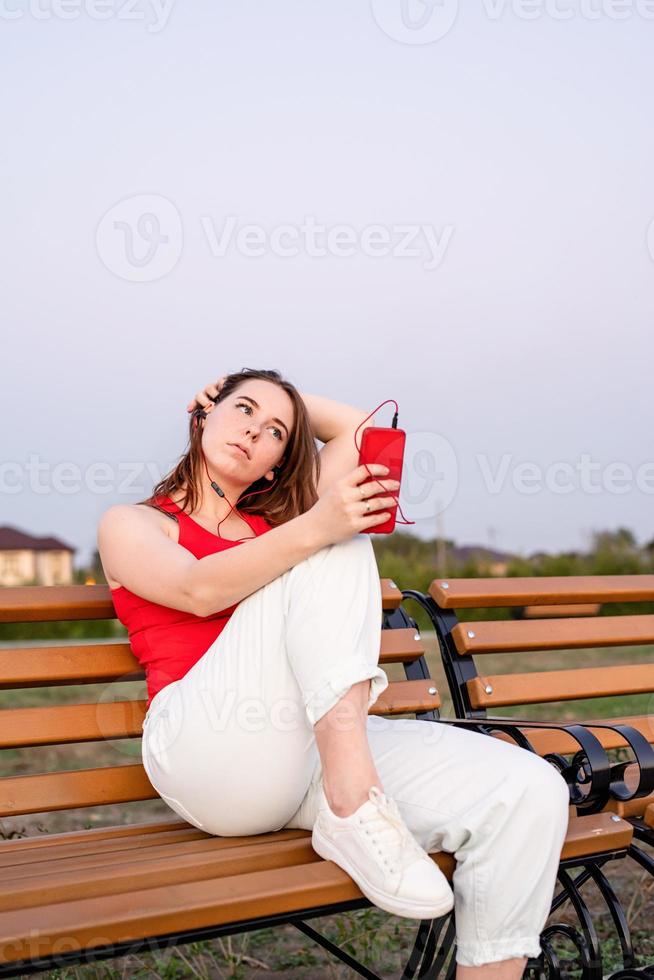 Pensativo joven adolescente sentado en un banco en el parque foto