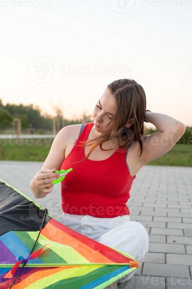 Young woman flying a kite in a public park at sunset photo