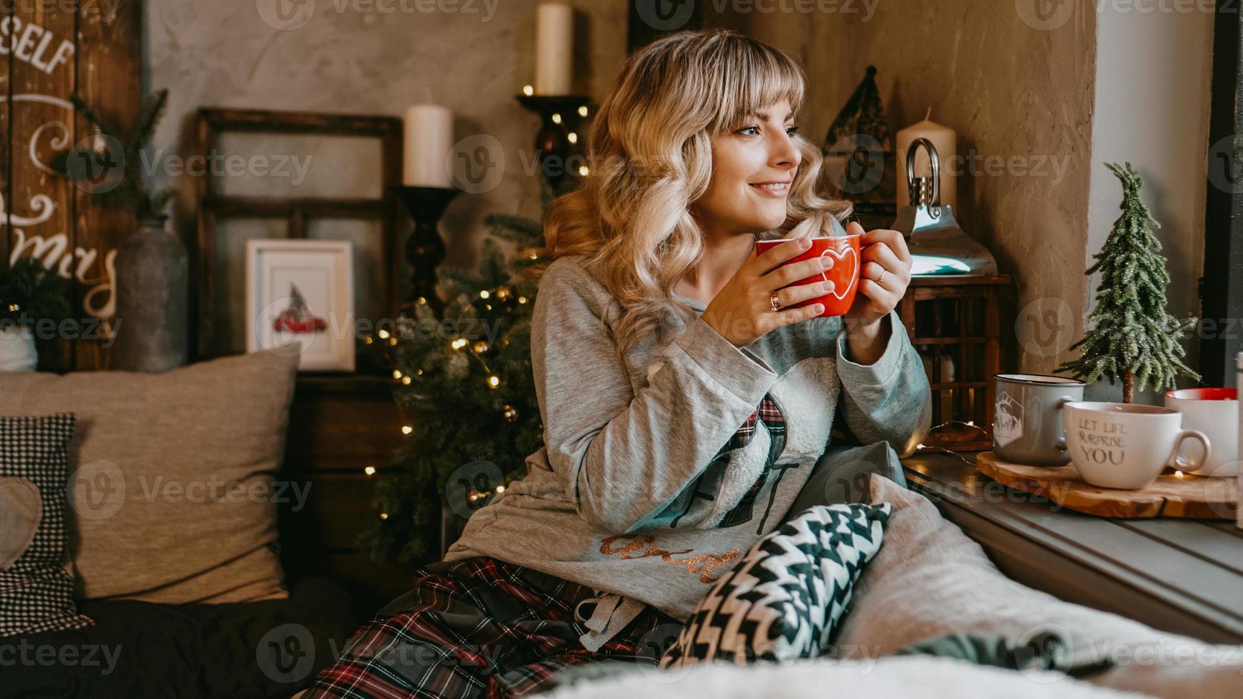 Young woman with cup of tea in Christmas cozy interior photo