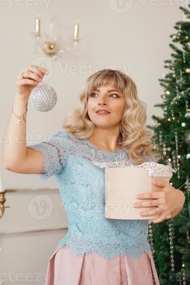 Young woman decorates Christmas tree with Christmas toys photo