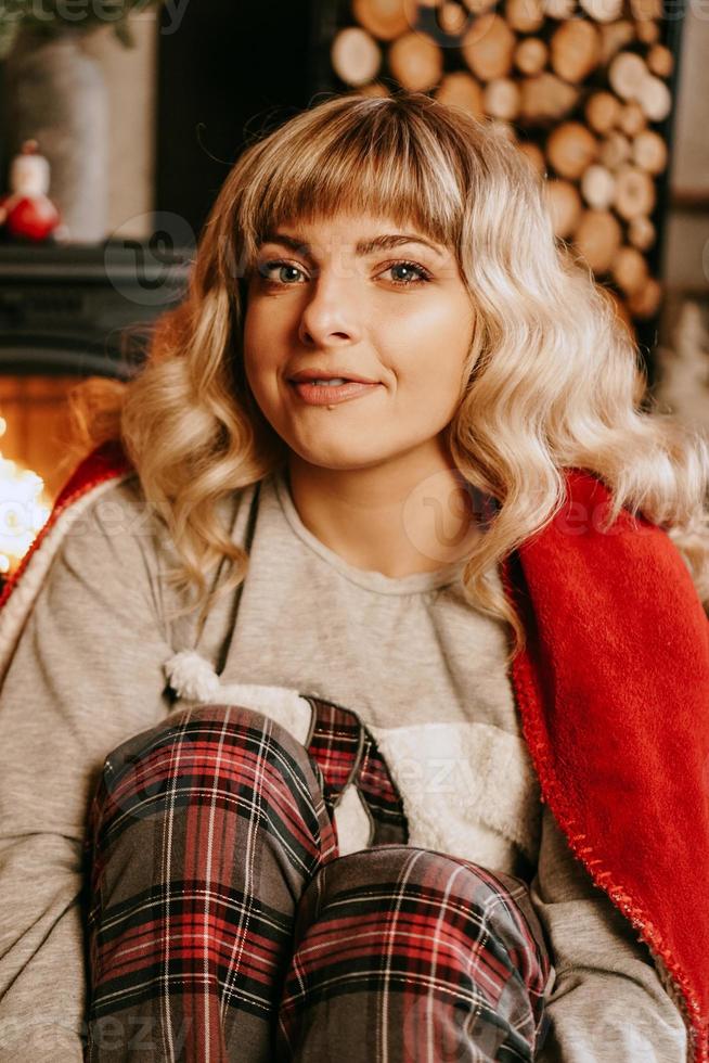 A beautiful young woman in a red plaid sits in New Year interior photo