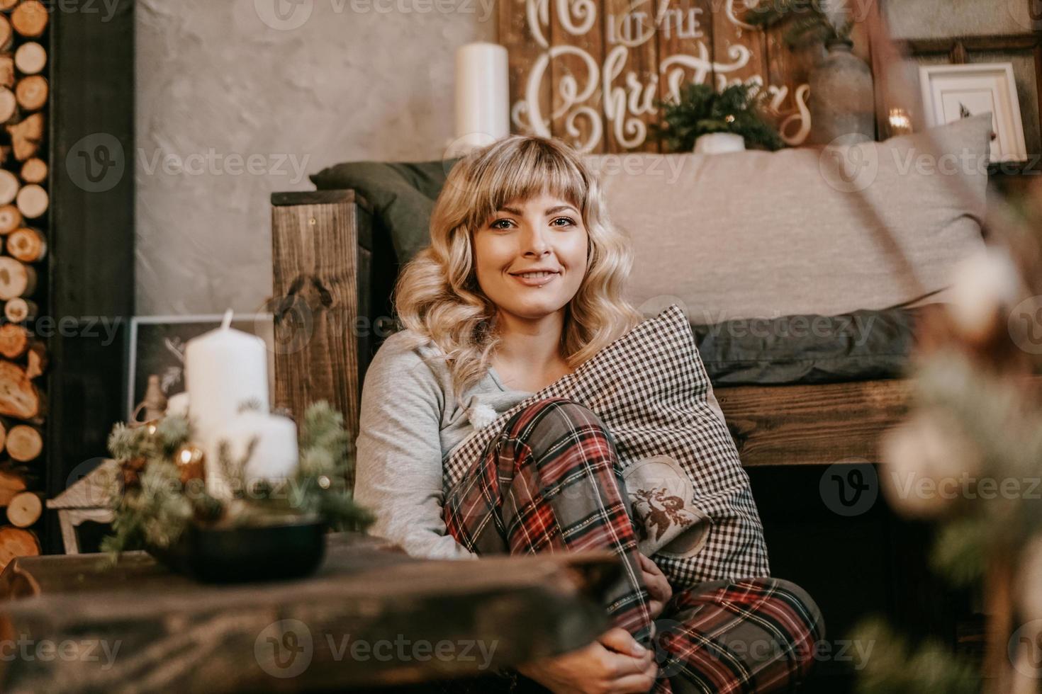 Young beautiful woman in pajamas near decorative fireplace photo