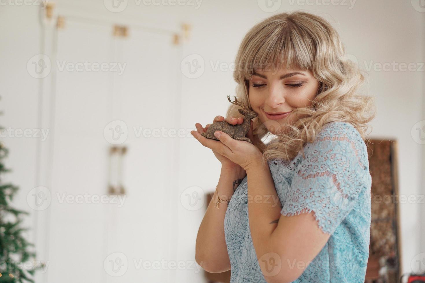 Wooden deer in the hands of young blonde photo