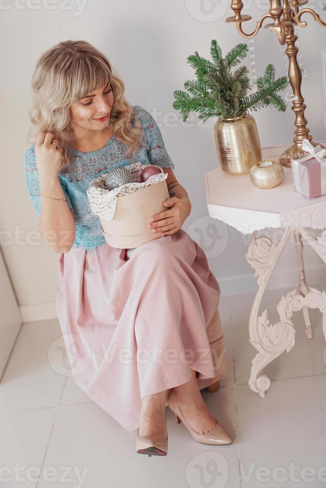 Young beautiful blonde woman holding a box of new year toys photo