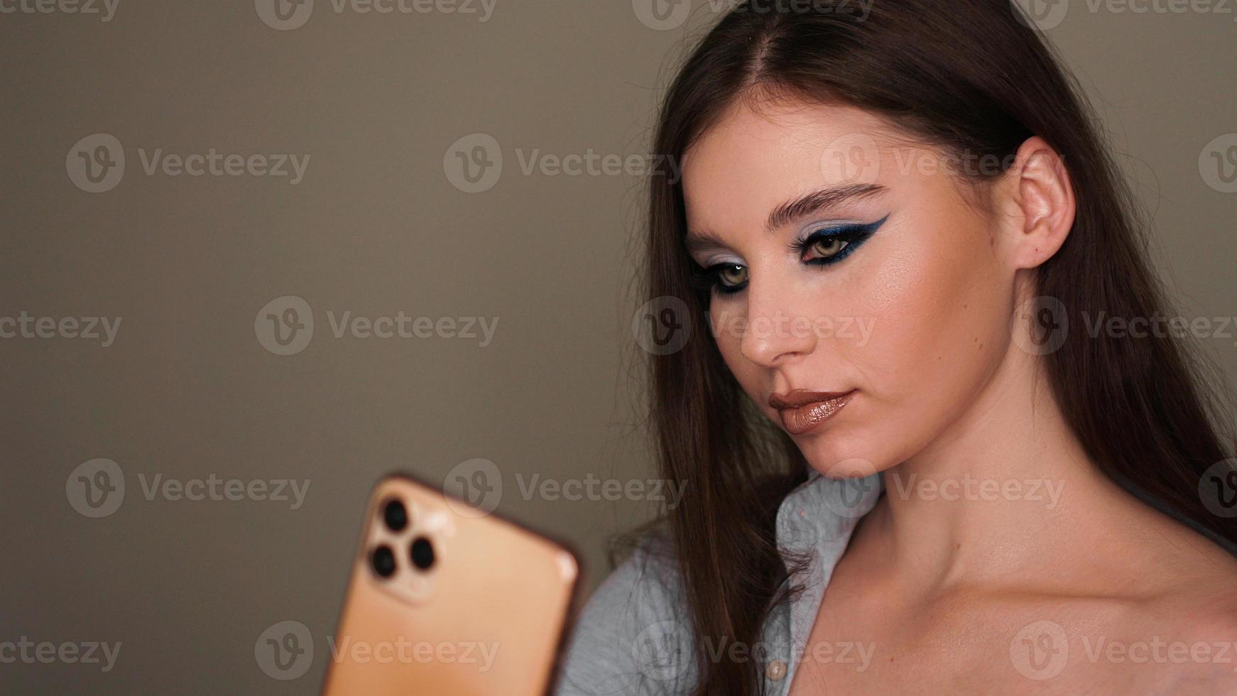 Modelo atractivo joven hacer un selfie después del maquillaje en el estudio de belleza foto