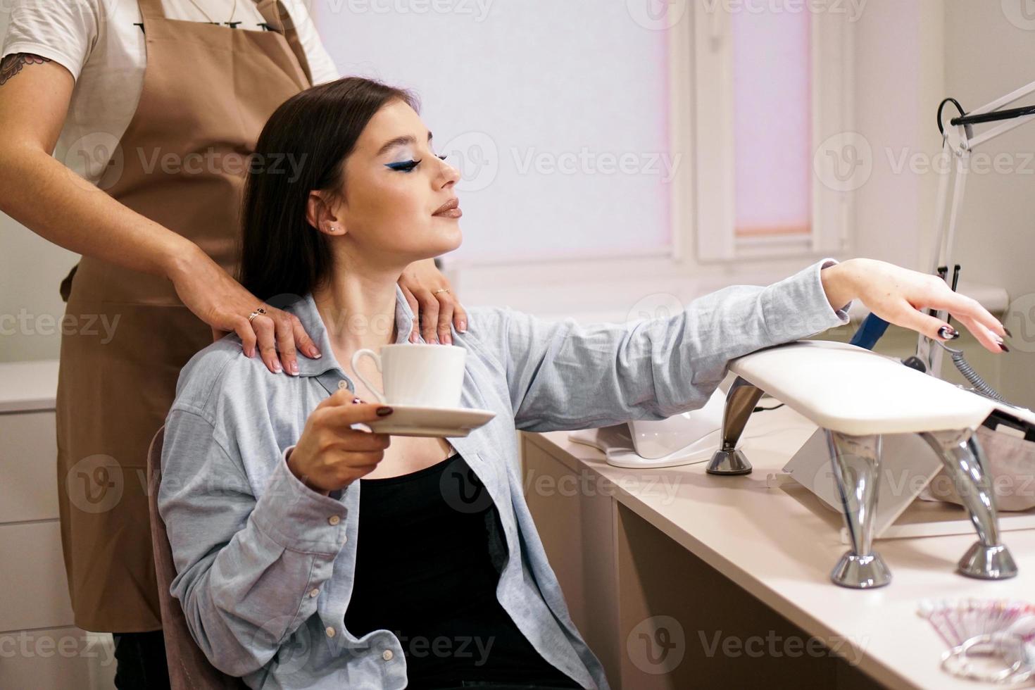 mujer recibiendo manicura y masaje al mismo tiempo en un salón foto