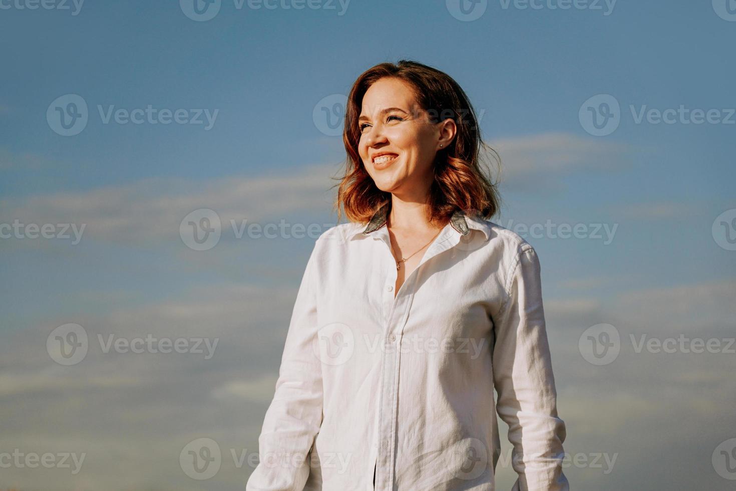 mujer feliz con una camisa blanca. retrato contra un cielo azul foto