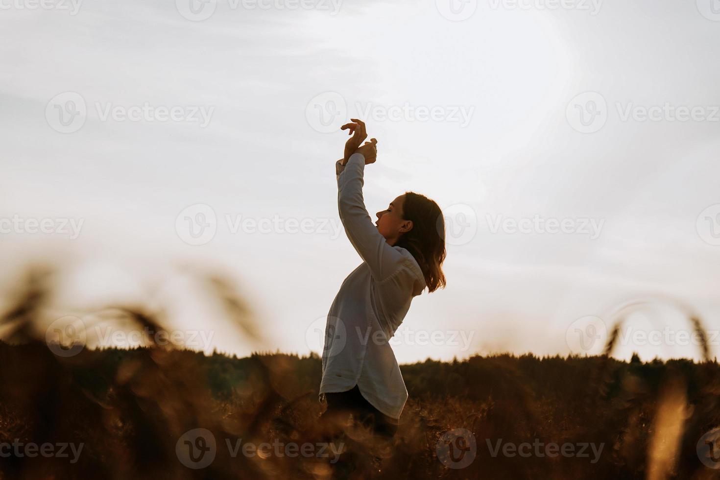 mujer disfrutando del atardecer. silueta femenina en el campo al atardecer foto