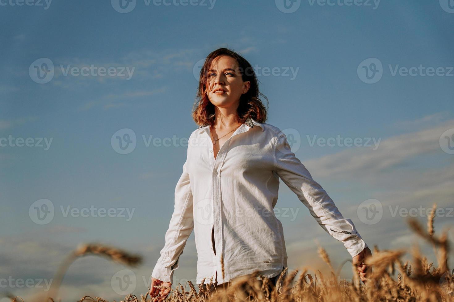 mujer joven feliz con una camisa blanca en un campo de trigo. día soleado. foto