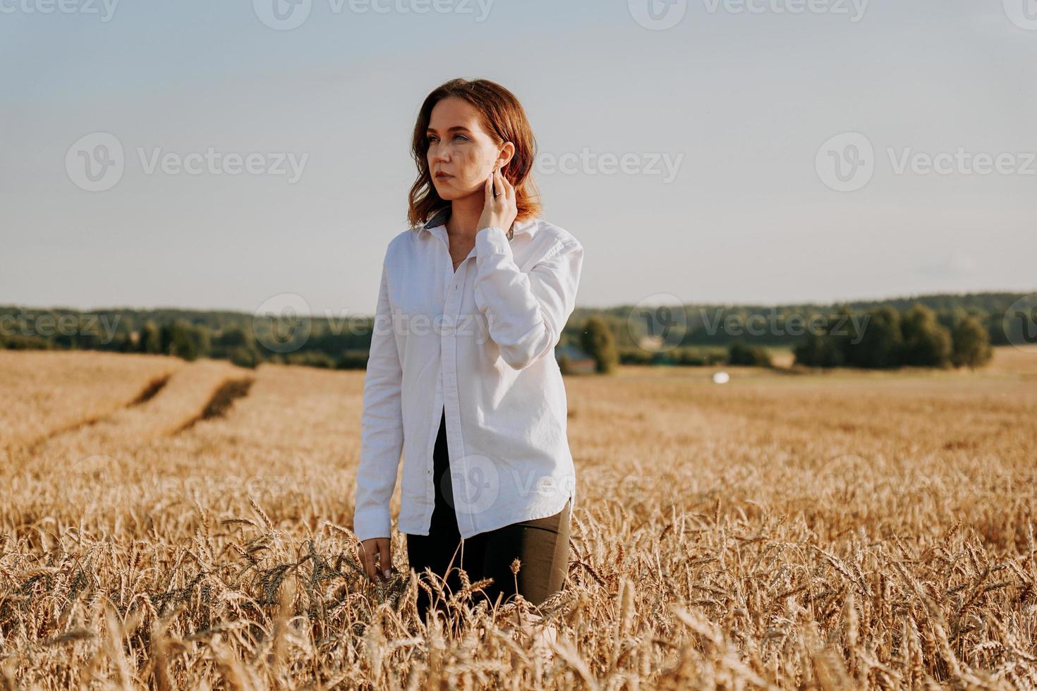 Red-haired girl in a white shirt. She in rye field on a sunny day photo