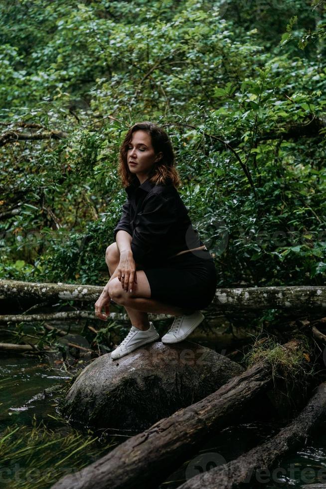 Woman in black clothes in a dark coniferous forest. Tracking and trip photo