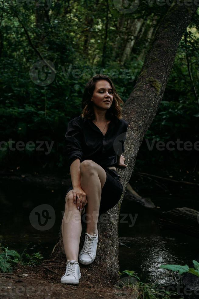 Woman in black clothes in a dark coniferous forest. Tracking and trip photo