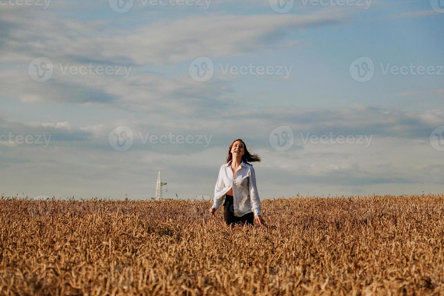 mujer corre en un campo de trigo en un día de verano. concepto de felicidad y alegría foto