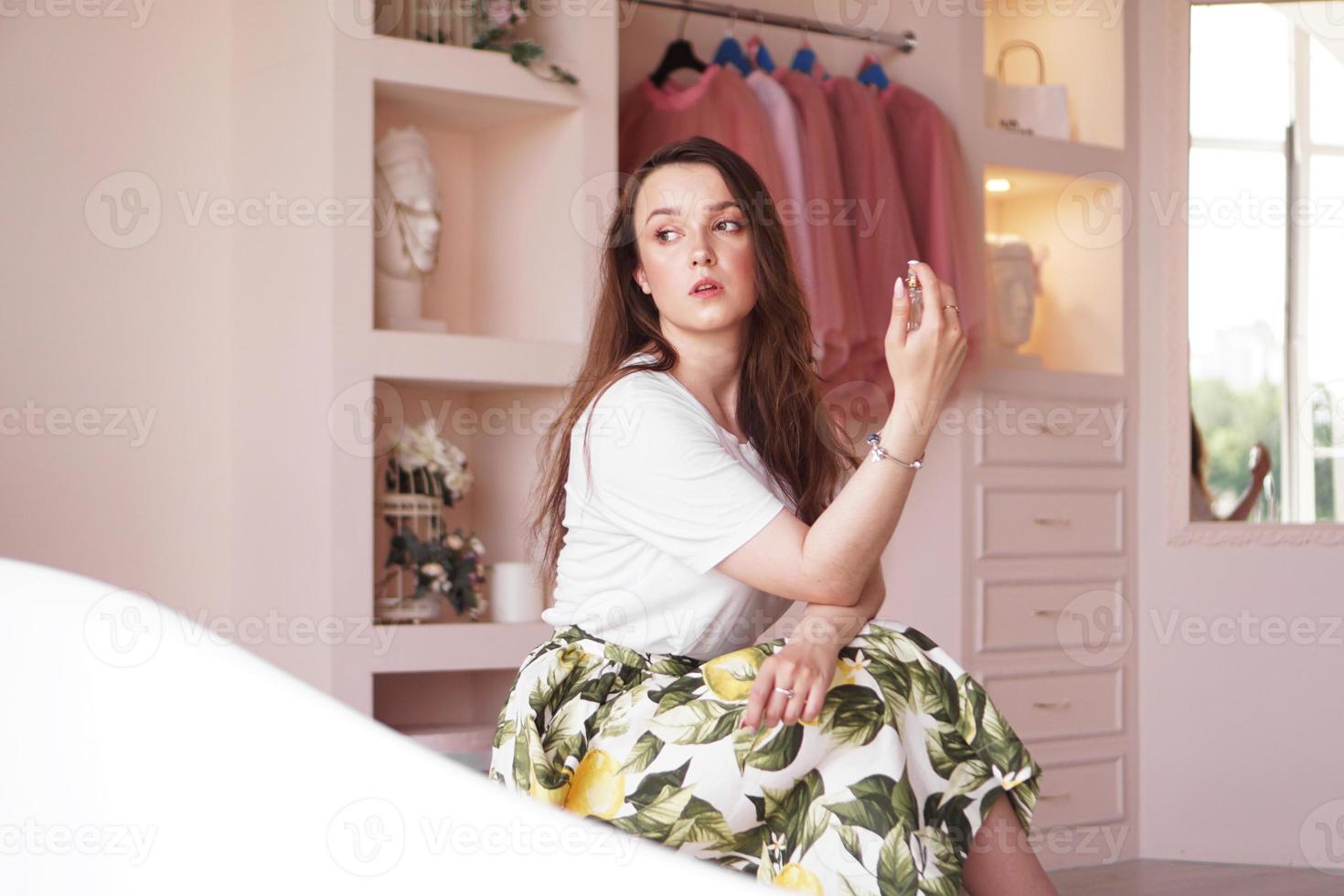 Beautiful young woman with bottle of perfume at home - dressing room photo