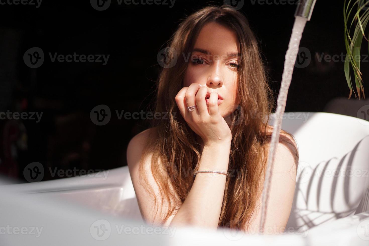 Una atractiva chica relajándose en el baño sobre fondo oscuro foto