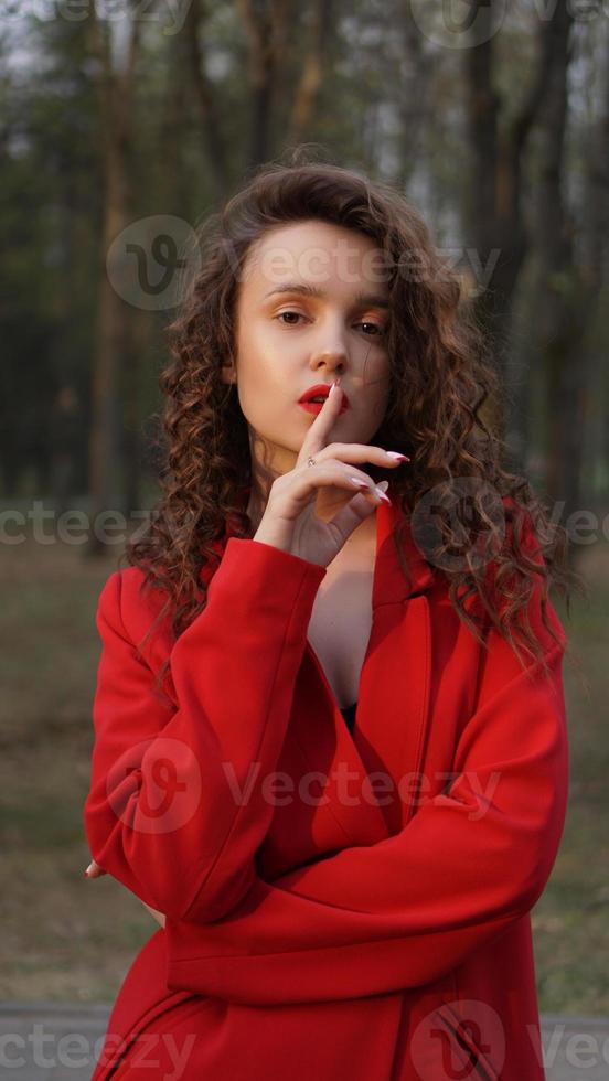 mujer glamorosa con traje rojo y brillo de labios rojo a juego. foto