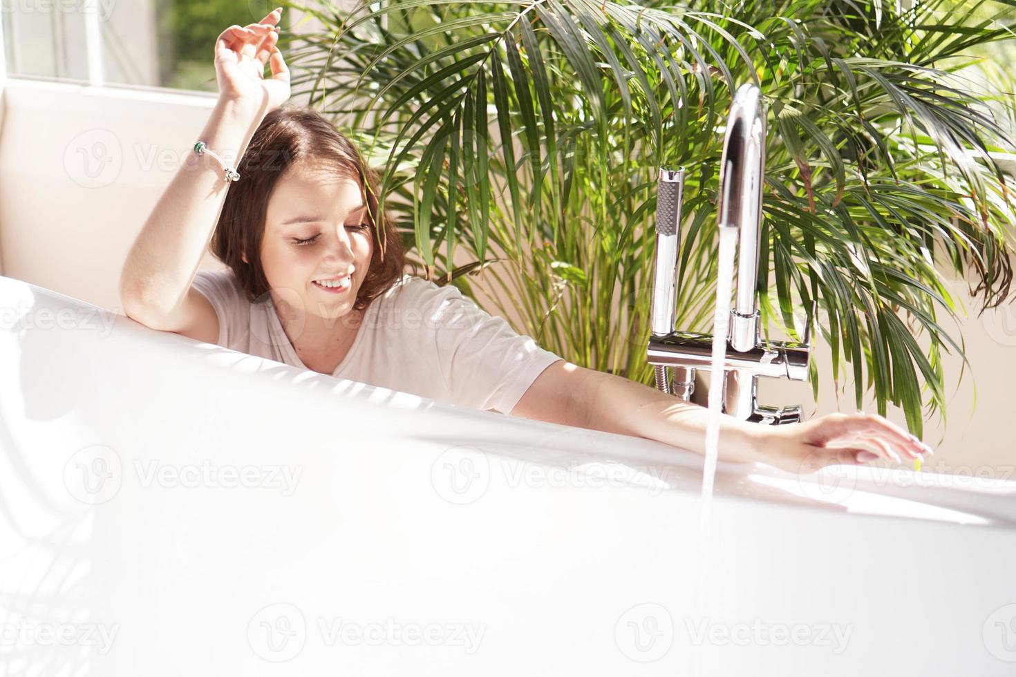 Think positive. Woman waits until the bathtub is filled with water photo