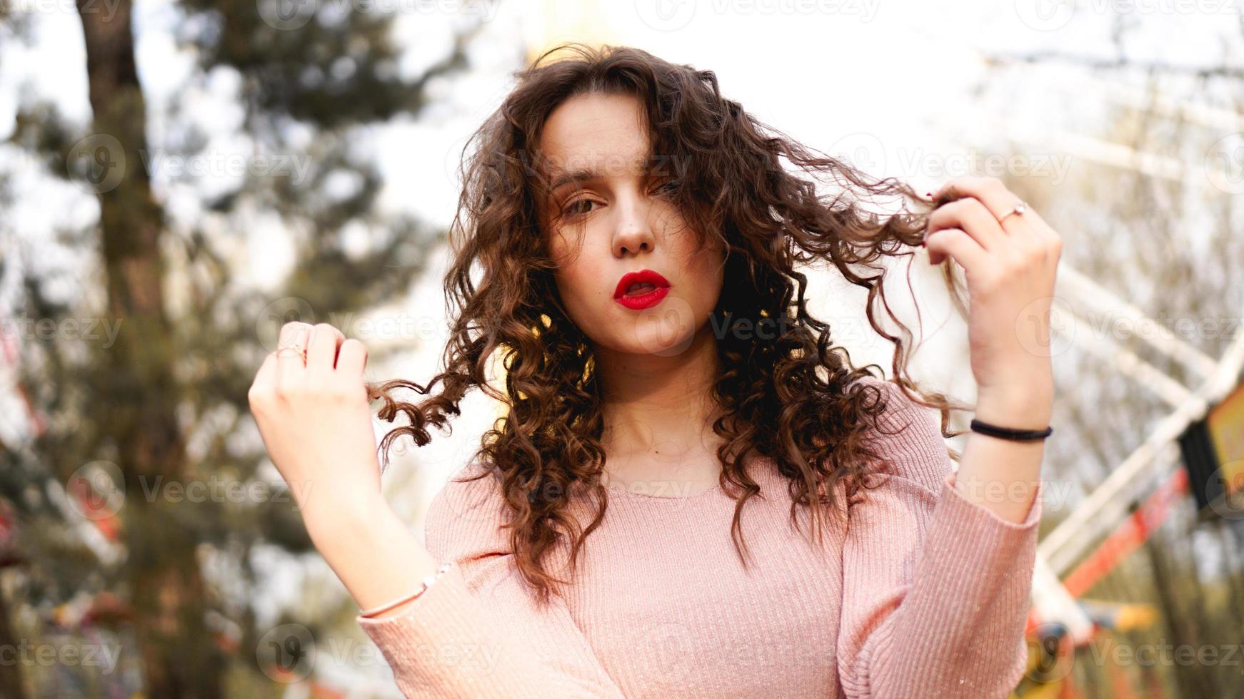 Women with long curly hair in the background of the Ferris wheel photo