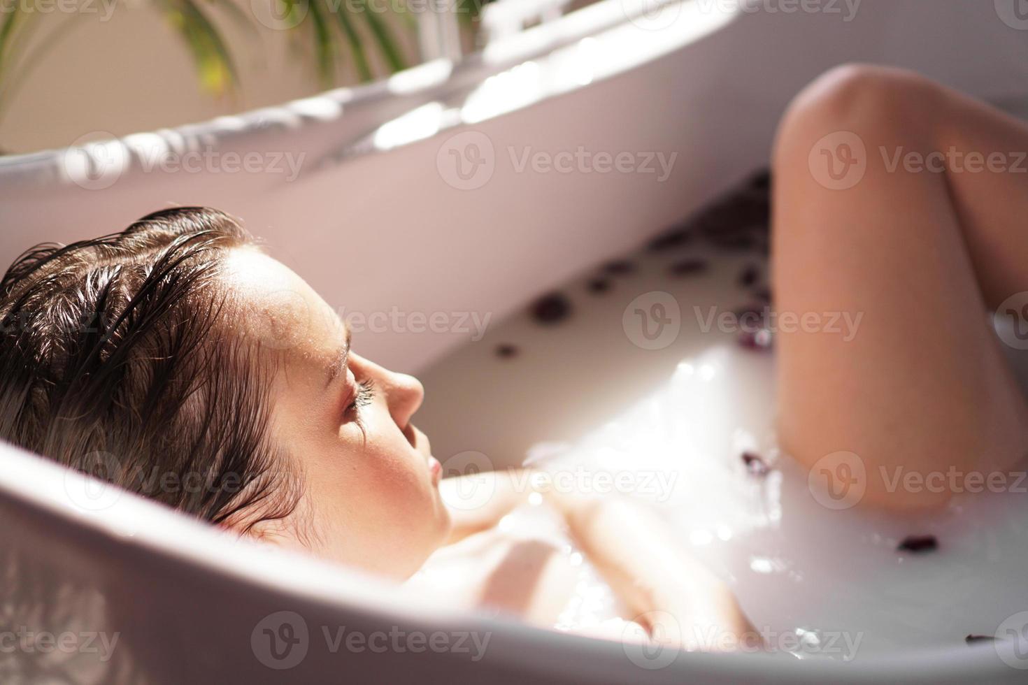 Una chica atractiva que se relaja en el baño sobre un fondo claro foto