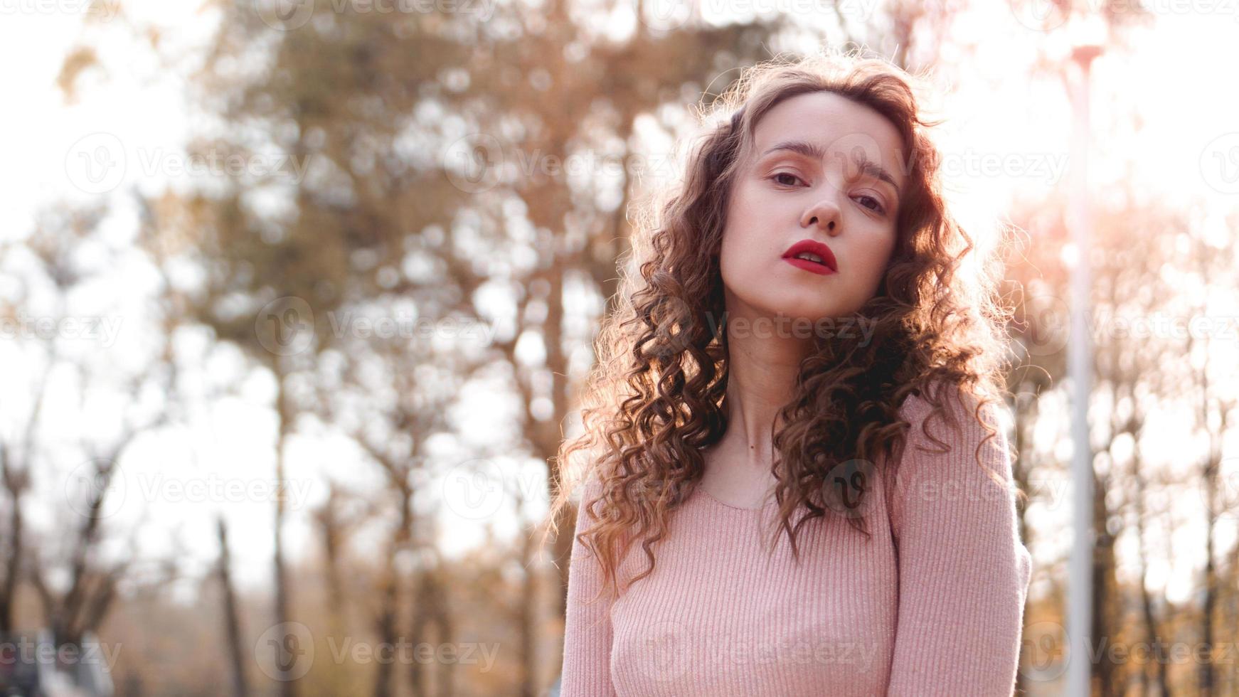 Primer plano de una joven y bella mujer con una puesta de sol detrás de ella foto