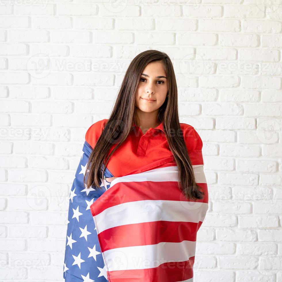 Hermosa mujer joven con bandera americana sobre fondo azul. foto