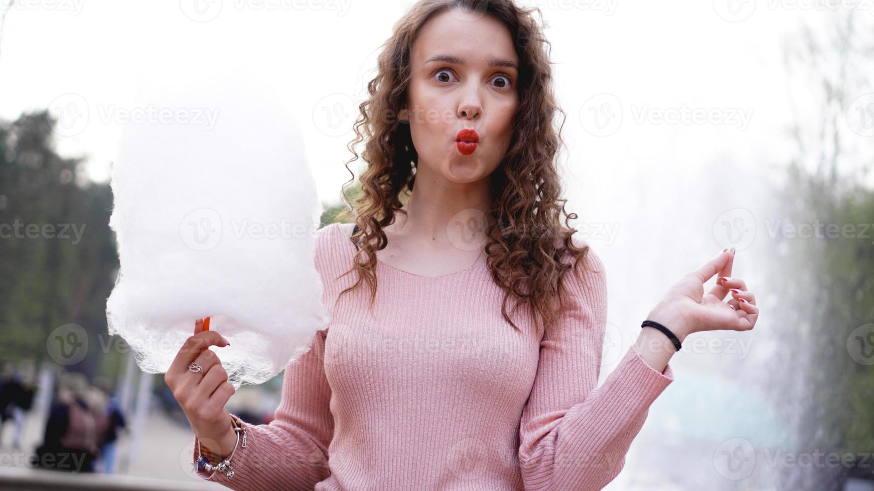 Smiling excited girl holding cotton candy at amusement park photo