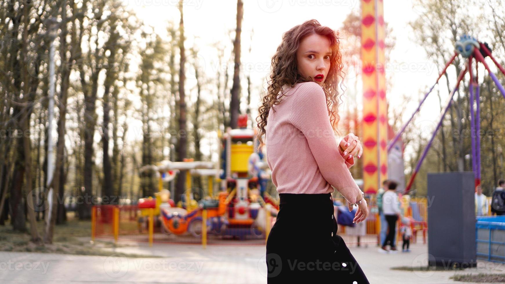 Exited smiling woman having fun at amusement park at hot summer day photo