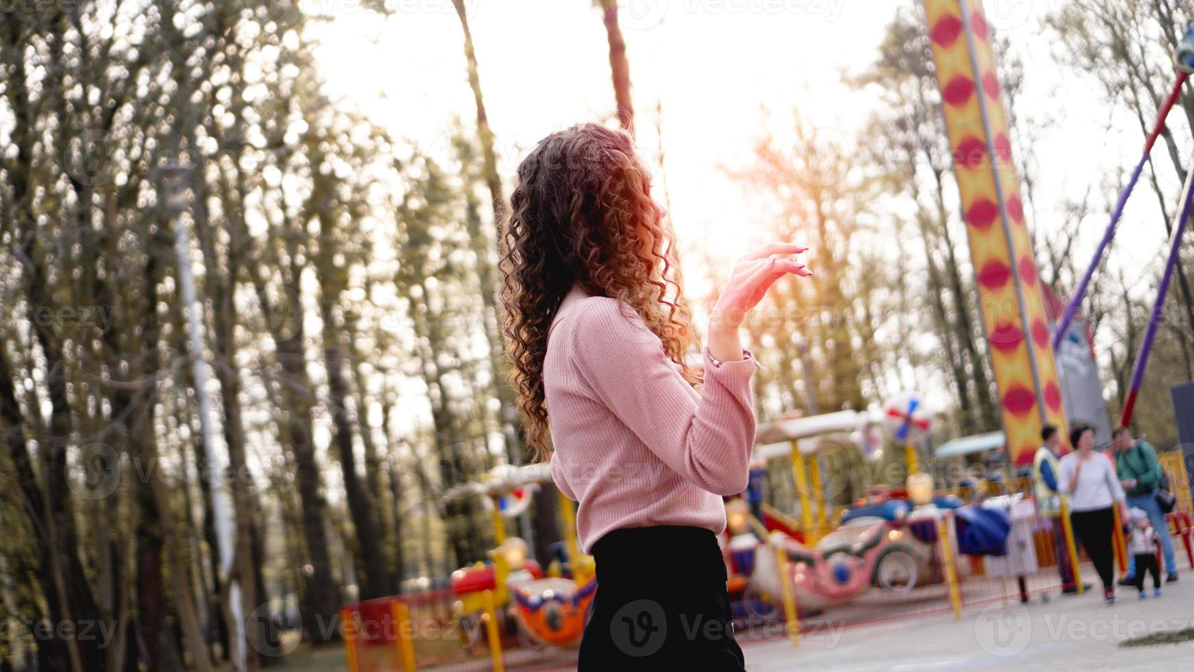 Exited smiling woman having fun at amusement park at hot summer day photo