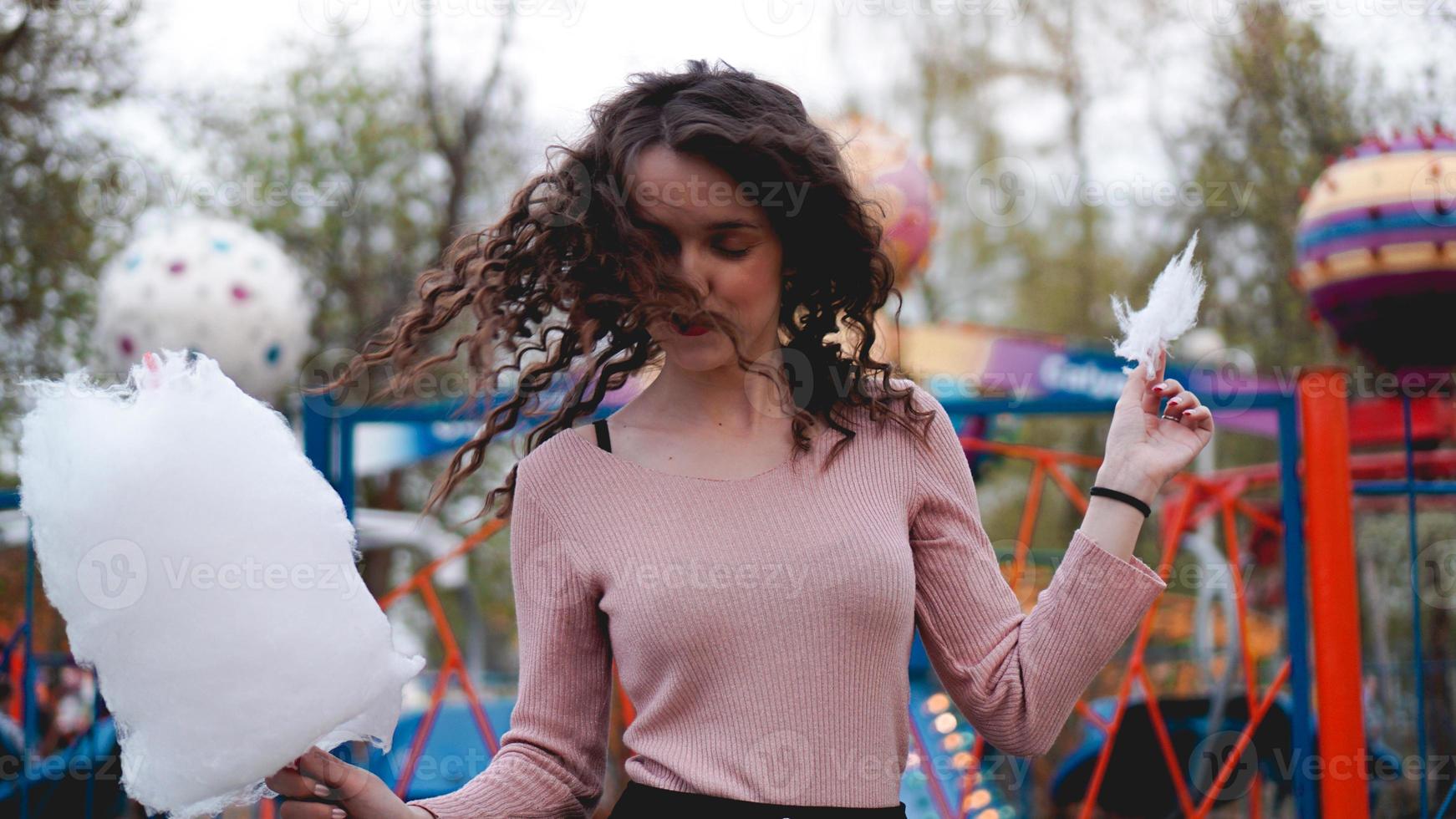 sonriente, emocionada, niña, tenencia, algodón de azúcar, en, parque de atracciones foto